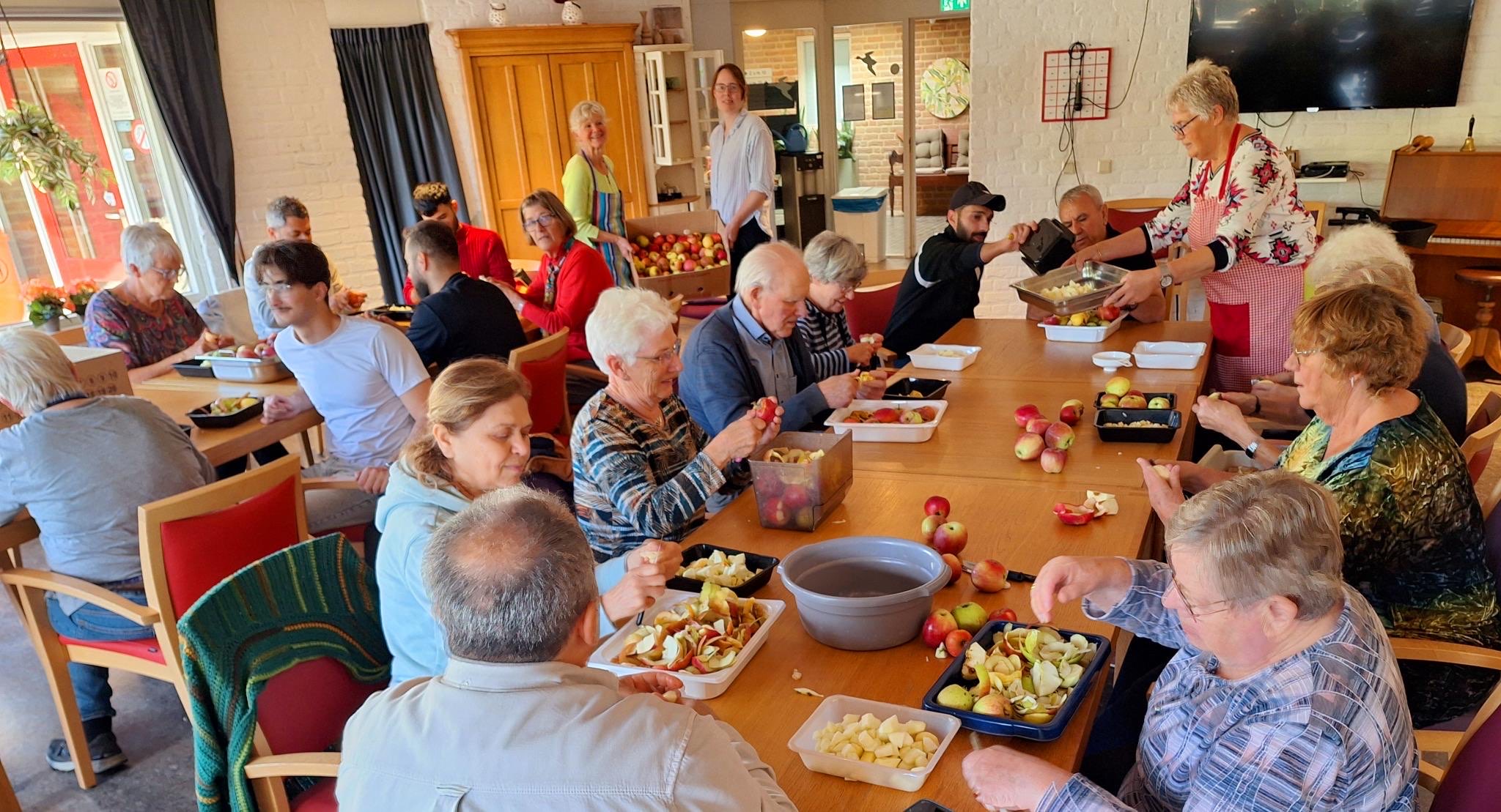 Vrijwilligers schillen appels aan tafel in het Korenhof